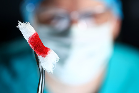 Surgeon in sterile uniform arms holding tools with bio material