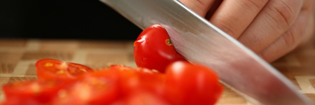 Cook holds knife in hand and cuts onの写真素材