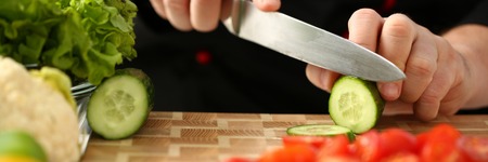 Cook holds knife in hand and cuts onの写真素材