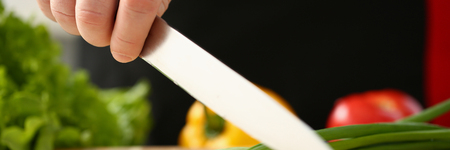 Cook holds knife in hand and cuts onの写真素材