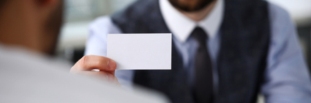 Male arm in suit give blank calling card to visitorの写真素材