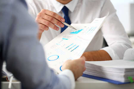 Group of businessmen with financial graph and silver penの写真素材