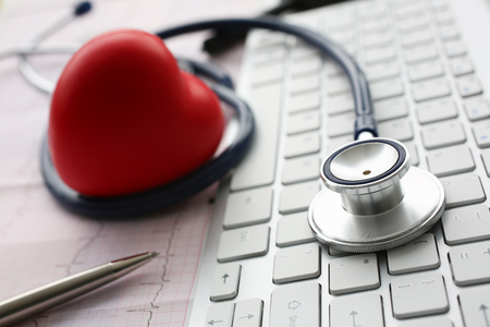 Stethoscope head lying on white keyboardの写真素材