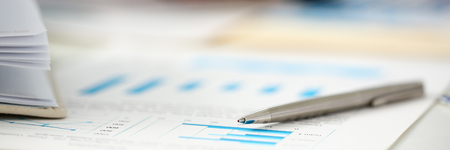 Silver pen lie on important paper at table with group of colleagues in background closeup. Paperwork job trade balance bank credit loan money invest payment irs commerce partnership conceptの写真素材