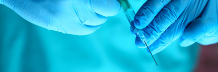 Physician injector arms in sterile uniform holding syringe while operating patient in surgical theatre closeup. HIV protection aids medication botulinum toxin innovation 911 team conceptの写真素材