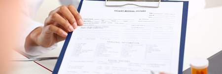 Female doctor hand hold silver pen and showing pad. Physical agreement form signature disease prevention ward round reception consent contract sign prescribe remedy healthy lifestyle conceptの写真素材