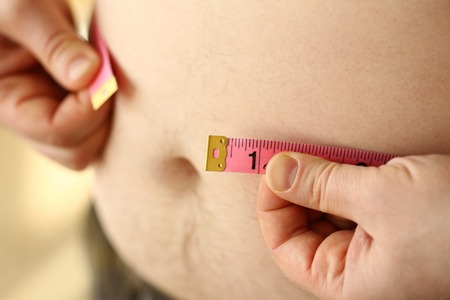 Thick man measuring belly with measuringの写真素材