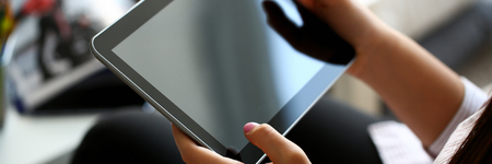 female hand holds tablet in home setting whileの写真素材