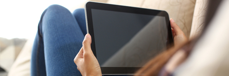 female hand holds tablet in home setting whileの写真素材