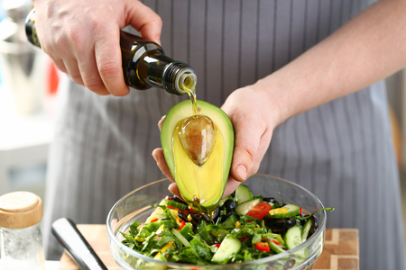 Male cook at home holds bottle of oliveの写真素材