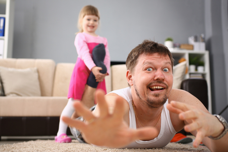 Cute little girl hold her father leg as proof of winning battle gameの写真素材