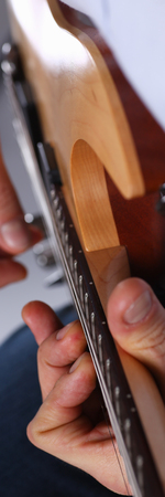 Male arms holding and playing classic shape wooden electric guitar closeup. Six stringed learning musical school education art leisure electrical vintage stage shop having fun enjoying hobby conceptの写真素材