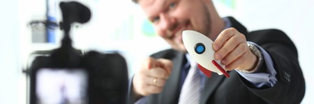 Businessman hold rocket in hand closeup on office background business conceptの写真素材