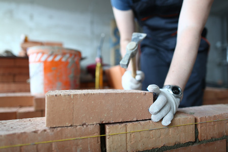 Skilled bricklayer putting red blockの写真素材
