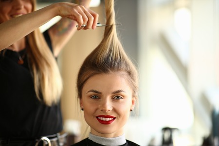 Hairdresser Holding Scissors on Smiling Woman Hairの写真素材