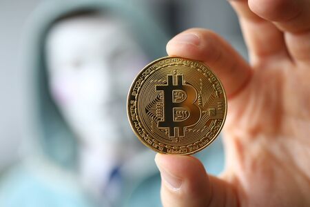 Hacker wear anonymus mask hold bitcoin in handのeditorial素材