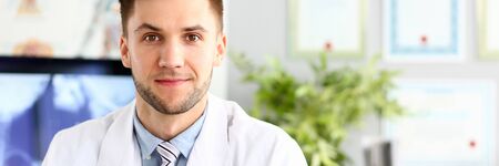 Handsome smiling medicine doctor sitting in officeの写真素材