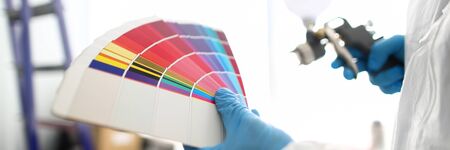 Hands of workman holding airbrush and colorful fantail picking wall tone to paintの写真素材