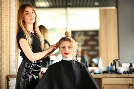 Hairdresser hands hold curling iron and makeの写真素材