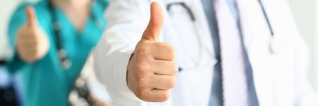 Two doctors show thumb up gesture with hands