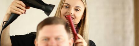Young Hairdresser Drying Male Hair by Blow Dryerの写真素材