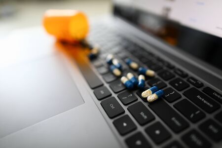 Yellow-blue pill capsules are scattered on black