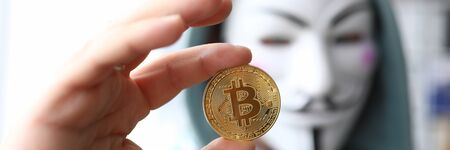Hacker wear anonymus mask hold bitcoin in handのeditorial素材