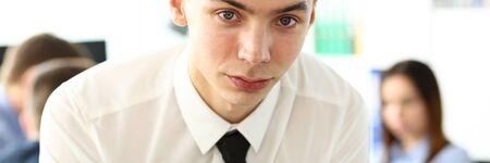 Young smiling clerk in shirt and tie holding financial chart clipped to pad looking in cameraの写真素材