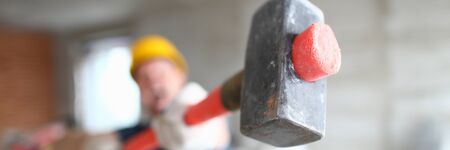 Focus on red sledgehammer craftman using special equipment to destroy and change construction site in order to improve and make room look better. Building conceptの写真素材