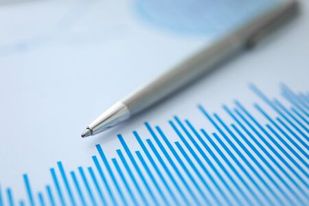 Silver pen lies on paper documents with color business charts background. Statistics financial...