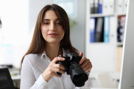 Portrait of pretty businesslady with modern camera. Wonderful woman looking with gladness and...