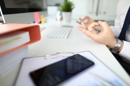 Businessman in office sits at table in relaxed pose. Situation control conceptの写真素材