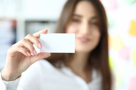 Focus on tender hand of smiling businesswoman showing special blank business card to friendly...