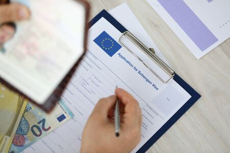 Male hand hold silver pen with passport. Filling Schengen apllication form conceptの写真素材