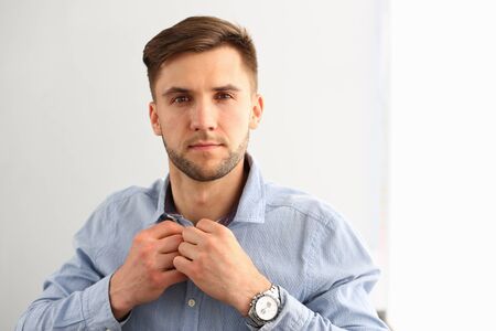 Portrait of confident male looking at camera with interest and confidence. Smart man wearing blue shirt and expensive watches in modern studio. Isolated on whiteの写真素材