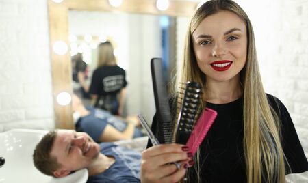Woman Hairdresser with Client and Hairbrush Tool. Female Hairstylist Holding Comb and Scissors in...