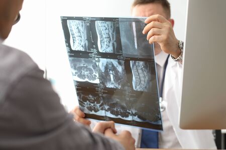 Doctor hold xray bone spine radiography in hand. Examination and treatment of intervertebral hernia....