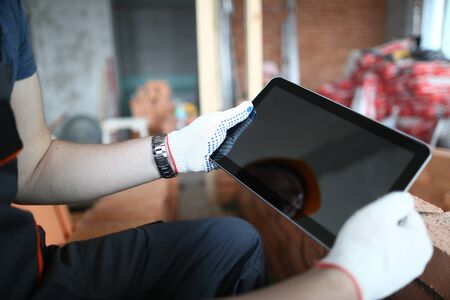 Close-up of male hands using smart tablet and watching something on high-tech technology. Builder...