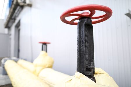 Huge industrial red valve on main heating pipeline closeup