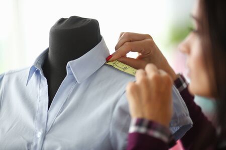 Close-up of trendy classy outfit measured by professional female tailor with special sewing...