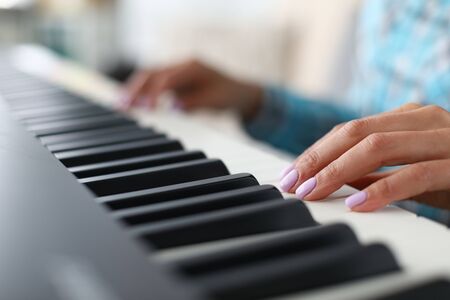 Close-up of female hands playing synthesizer in music workshop. Professional cute pianist creating new musical composition. Art concept. Blurred backgroundの写真素材