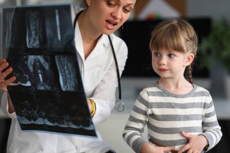 Child doctor specialist look x-ray image in hospital office portrait. Bone tratment conceptの写真素材