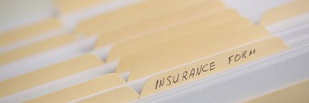A stack of papers in filing cabinet with inscription insurance form backgroundの写真素材
