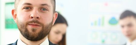 Focus on concentrated man working in big modern building and looking at camera with joy. Smart people discussing complicated business contract or strategy. Company meeting concept. Blurred backgroundの写真素材