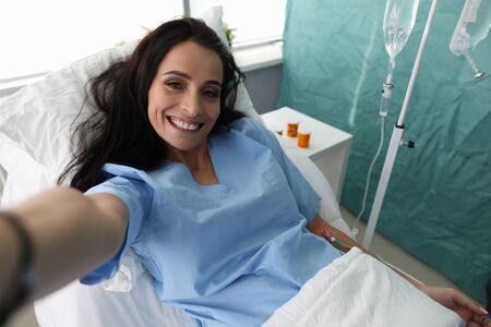 Beauty woman make selfie photo in hospital ward portrait. Social media addict conceptの写真素材