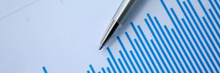 Silver pen lies on paper documents with color business charts background. Statistics financial...