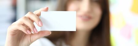 Focus on tender hand of smiling businesswoman showing special blank business card to friendly colleague or partner. Copy space on biz pasteboard. Blurred backgroundの写真素材