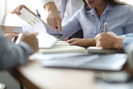 Focus on male businessman hand pointing on mistake in annual statement. Workteam discussing...
