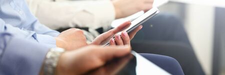 Focus on female hands holding modern smartphone. Business people writing something in important...