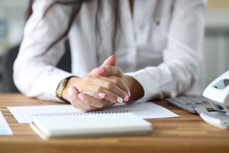 Close-up of tender female hands with fashionable manicure. Businesswoman wearing formal clothes sitting by table with notebooks, documents and calculator. HR manager at workplaceの写真素材